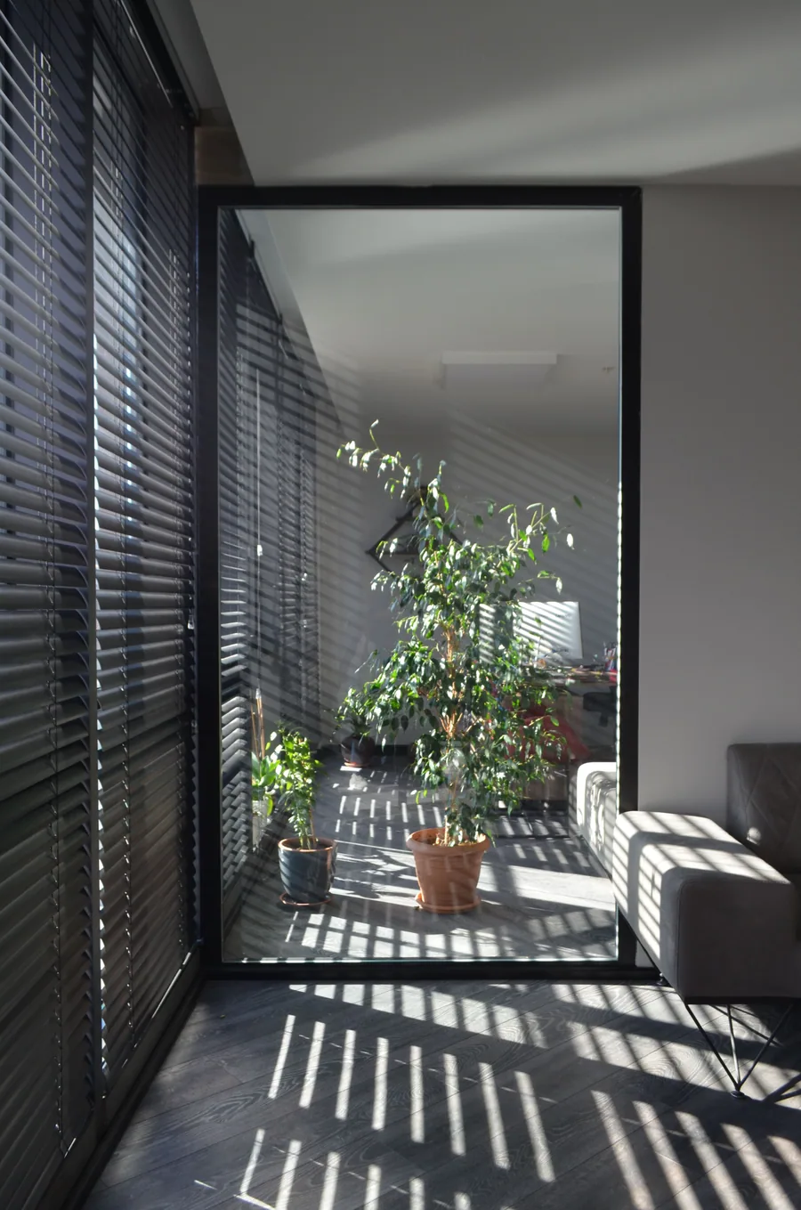 Venetian blinds casting architectural shadows in a bright living room